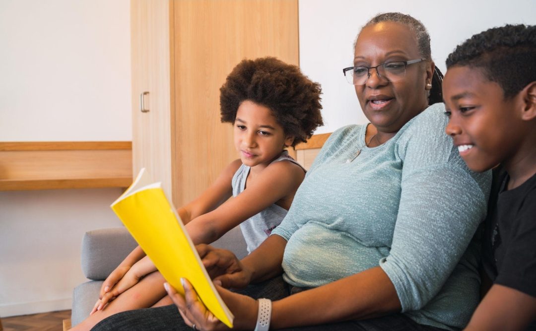 Une grand-mère lit un livre avec ses petits-enfants